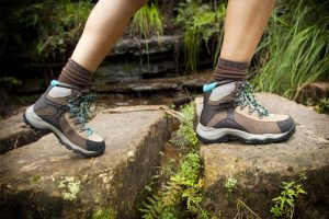 hombre andando por unas rocas con botas de talle alto