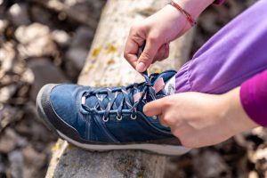 mujer atándose los cordones de su calzado para excursiones