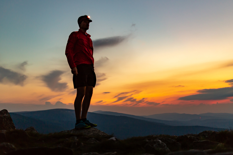 Hombre en la cima de una montaña al atardecer mientras está corriendo