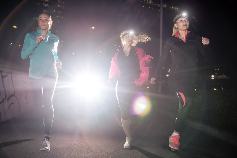 Tres mujeres haciendo running por la noche con linternas frontales
